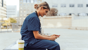 Female travel nurse smiling down at her phone, scrolling through PRN shifts through Matchwell